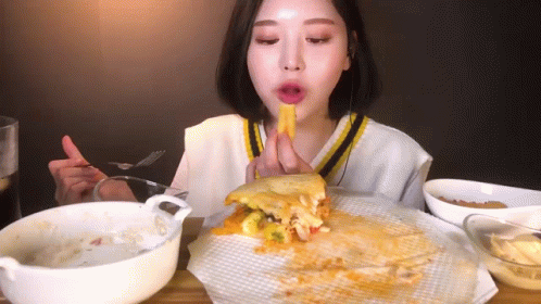 A Woman Is Eating A Sandwich With A Fork And Knife . GIF