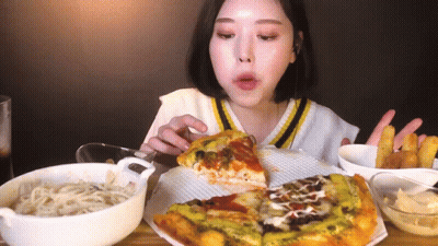 A Woman Is Eating A Slice Of Pizza And French Fries . GIF