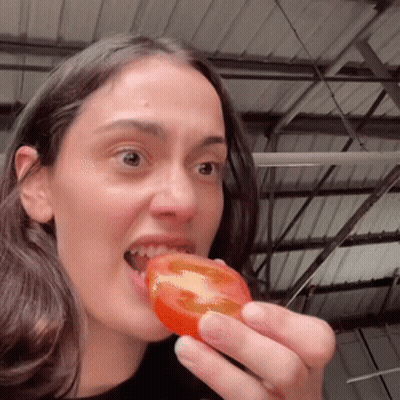 A Woman Is Eating A Slice Of Tomato With Her Mouth Open GIF