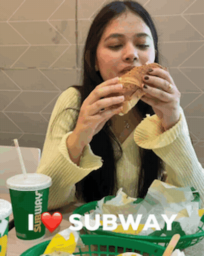 A Woman Is Eating A Subway Sandwich And Drinking A Subway Cup GIF