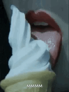 A Woman Is Eating An Ice Cream Cone With Her Tongue Hanging Out . GIF
