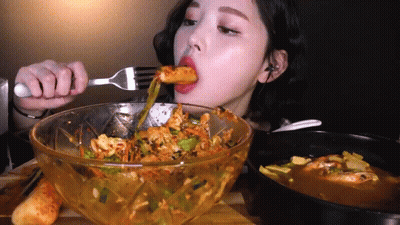A Woman Is Eating Food With A Fork From A Bowl GIF