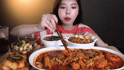 A Woman Is Eating Food With Chopsticks And A Bowl Of Soup GIF