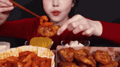 A Woman Is Eating Fried Chicken With Chopsticks And A Spoon . GIF
