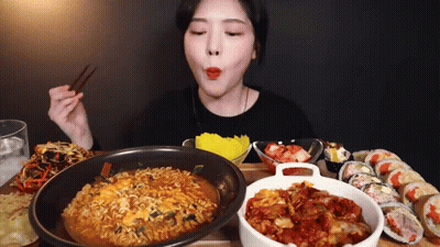 A Woman Is Eating Ramen And Sushi With Chopsticks . GIF