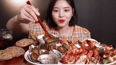 A Woman Is Eating Seafood With Chopsticks And A Spoon . GIF