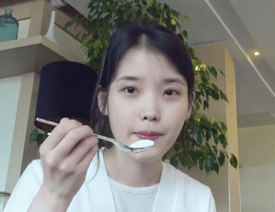 A Woman Is Eating Something With A Spoon GIF
