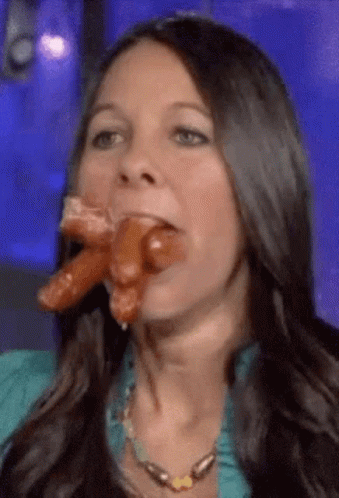 A Woman Is Eating Two Sausages In Her Mouth . GIF