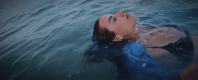 A Woman Is Floating On Her Back In The Water GIF