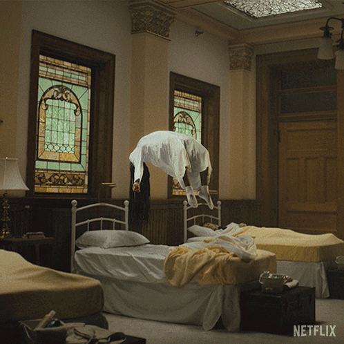 A Woman Is Flying Through The Air In A Room With Netflix Written On The Bottom GIF