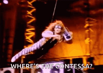 A Woman Is Flying Through The Air While Holding A Microphone And Says `` Where 'S The Contessa ? '' GIF