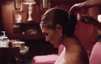 A Woman Is Getting Her Hair Done By A Man While Sitting On A Couch . GIF