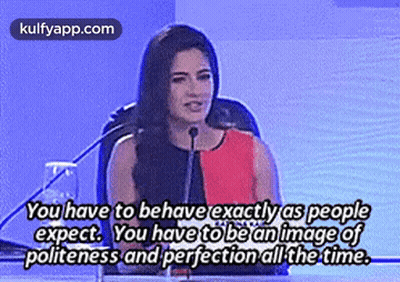 A Woman Is Giving A Speech In Front Of A Microphone With A Quote About Politeness And Perfection All The Time . GIF