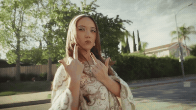 A Woman Is Giving The Middle Finger While Standing On The Sidewalk GIF