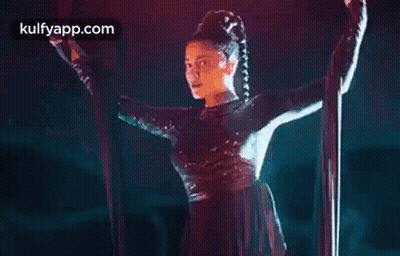 A Woman Is Hanging From A Rope In A Dark Room . GIF