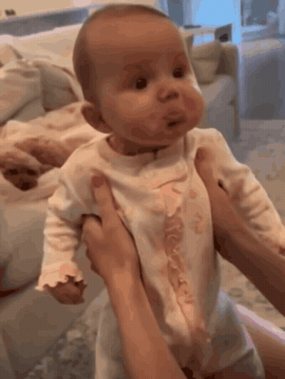 A Woman Is Holding A Baby In Her Arms And Making A Face GIF