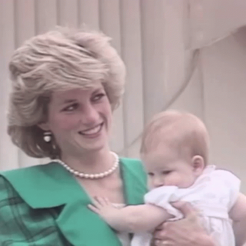 A Woman Is Holding A Baby In Her Arms And Smiling . GIF