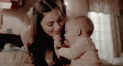 A Woman Is Holding A Baby In Her Arms In A Bedroom . GIF