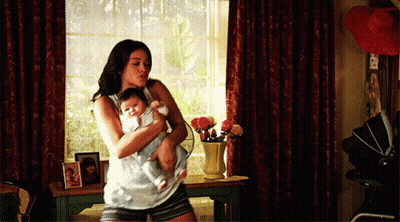 A Woman Is Holding A Baby In Her Arms In A Room GIF