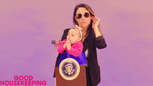 A Woman Is Holding A Baby In Her Arms While Standing At A Podium . GIF