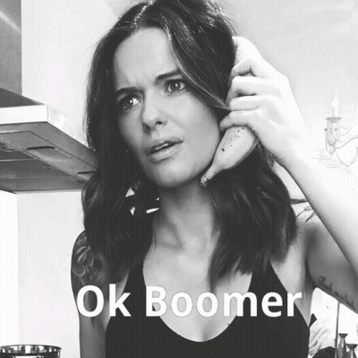 A Woman Is Holding A Banana To Her Ear With The Words Ok Boomer Written Below Her GIF