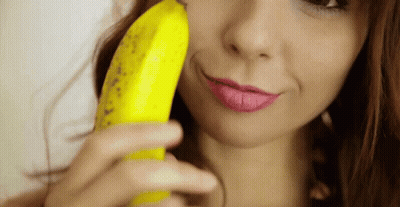 A Woman Is Holding A Banana To Her Face GIF