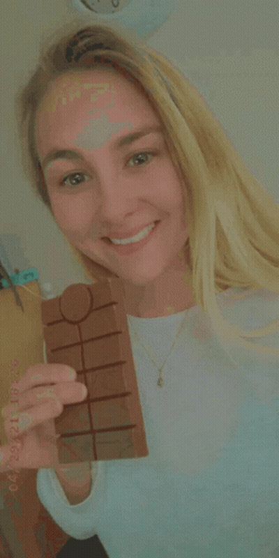 A Woman Is Holding A Bar Of Chocolate In Her Hand With A Date Stamp Of 04/21 GIF