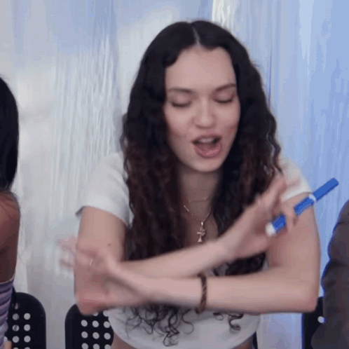 A Woman Is Holding A Blue Marker In Her Hand GIF