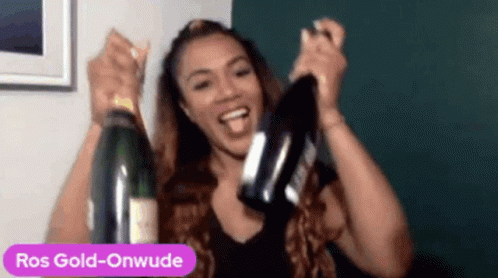 A Woman Is Holding A Bottle Of Ros Gold-Onwude Champagne . GIF