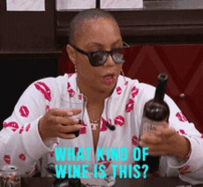 A Woman Is Holding A Bottle Of Wine And A Glass Of Wine And Asking What Kind Of Wine Is This ? GIF