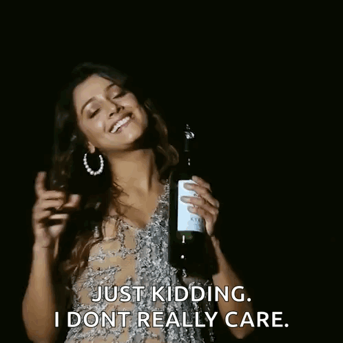 A Woman Is Holding A Bottle Of Wine And Smiling . GIF