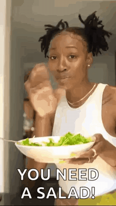 A Woman Is Holding A Bowl Of Salad And Eating It With A Fork . GIF
