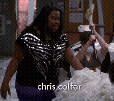 A Woman Is Holding A Broom And The Name Chris Colfer Is On The Bottom GIF