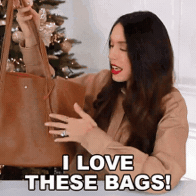 A Woman Is Holding A Brown Tote Bag And Saying I Love These Bags . GIF