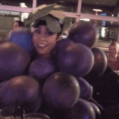 A Woman Is Holding A Bunch Of Balloons And Smiling . GIF