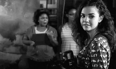 A Woman Is Holding A Camera In Front Of A Group Of Women . GIF