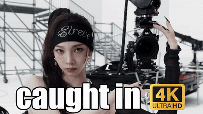 A Woman Is Holding A Camera With The Words Caught In 4K Ultra Hd GIF