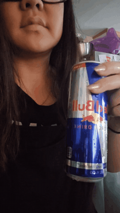 A Woman Is Holding A Can Of Red Bull Energy Drink GIF