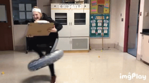 A Woman Is Holding A Cardboard Box And A Balloon In A Room With A Sign That Says Imgplay On It GIF