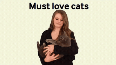 A Woman Is Holding A Cat In Her Arms With The Words Must Love Cats Behind Her GIF