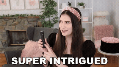A Woman Is Holding A Cell Phone And The Words Super Intrigued Are On The Screen GIF