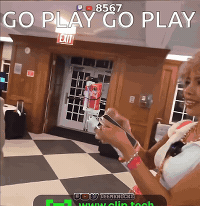 A Woman Is Holding A Cell Phone In Front Of A Sign That Says Exit GIF
