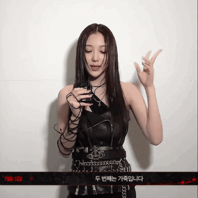 A Woman Is Holding A Cell Phone In Front Of A Sign That Says Yin Seo GIF