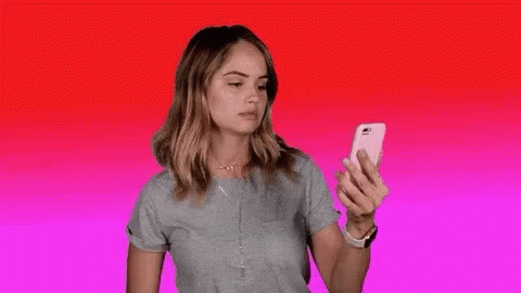 A Woman Is Holding A Cell Phone In Her Hand And The Word Blocked Is Visible . GIF
