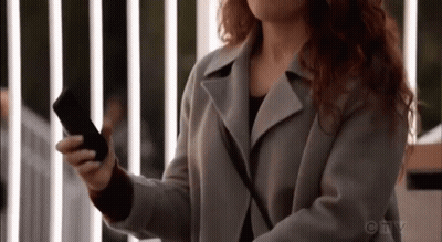 A Woman Is Holding A Cell Phone In Her Hand . GIF