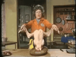 A Woman Is Holding A Chicken On A Cutting Board . GIF