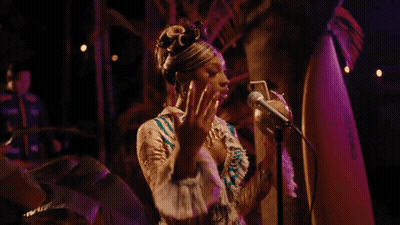 A Woman Is Holding A Coconut In Front Of A Microphone . GIF