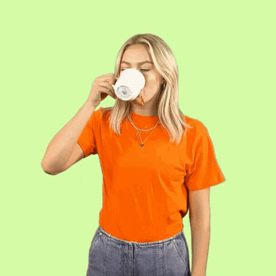 A Woman Is Holding A Cup Of Coffee And Making A Funny Face . GIF
