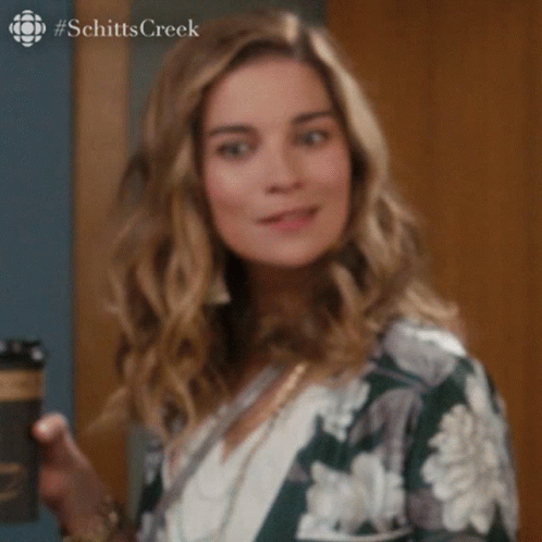 A Woman Is Holding A Cup Of Coffee And Making A Funny Face . GIF