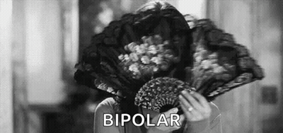 A Woman Is Holding A Fan In Front Of Her Face And The Word Bipolar Is Written Above Her . GIF